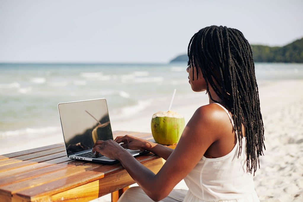 Young woman working on computer on beach